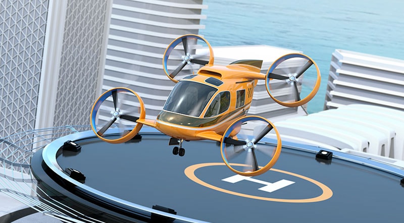 A drone helicopter in yellow launching a a helipad