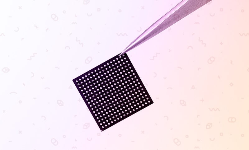 a computer chip being held by pliers