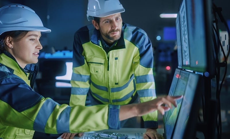 A woman engineer looking at a screen with male engineer standing next to her