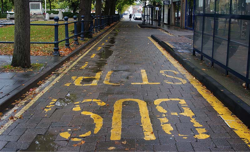 a black roaded with faded yellow markings stating Bus Stop